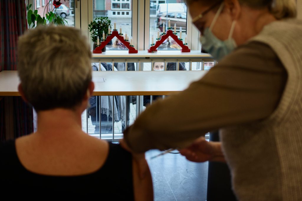 Vaccinering af beboere og ansatte på Lollandshus plejehjem i Aalborg. Plejehjemsleder Tina Olsen bliver vaccineret, mens ansatte der venter på at det bliver deres tur, følger med gennem vinduet.
